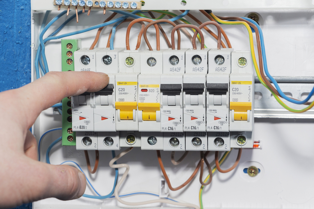 Electrical panel with person flipping switch. | Residential Electrician Services