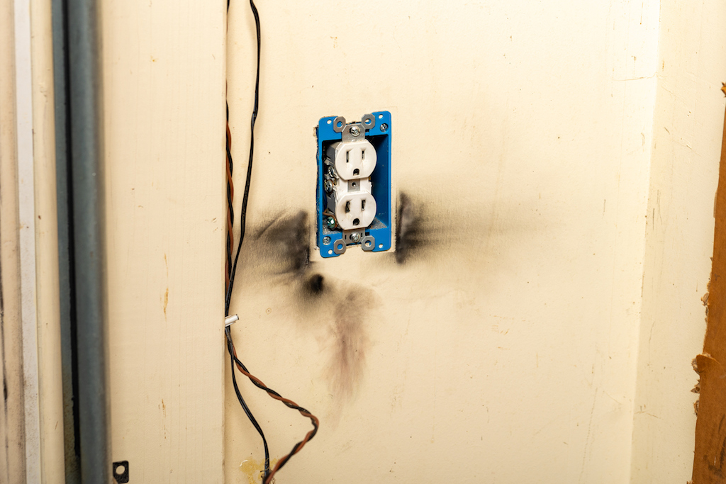 A burnt outlet after an electrical surge at home. In need of electrical repair. 