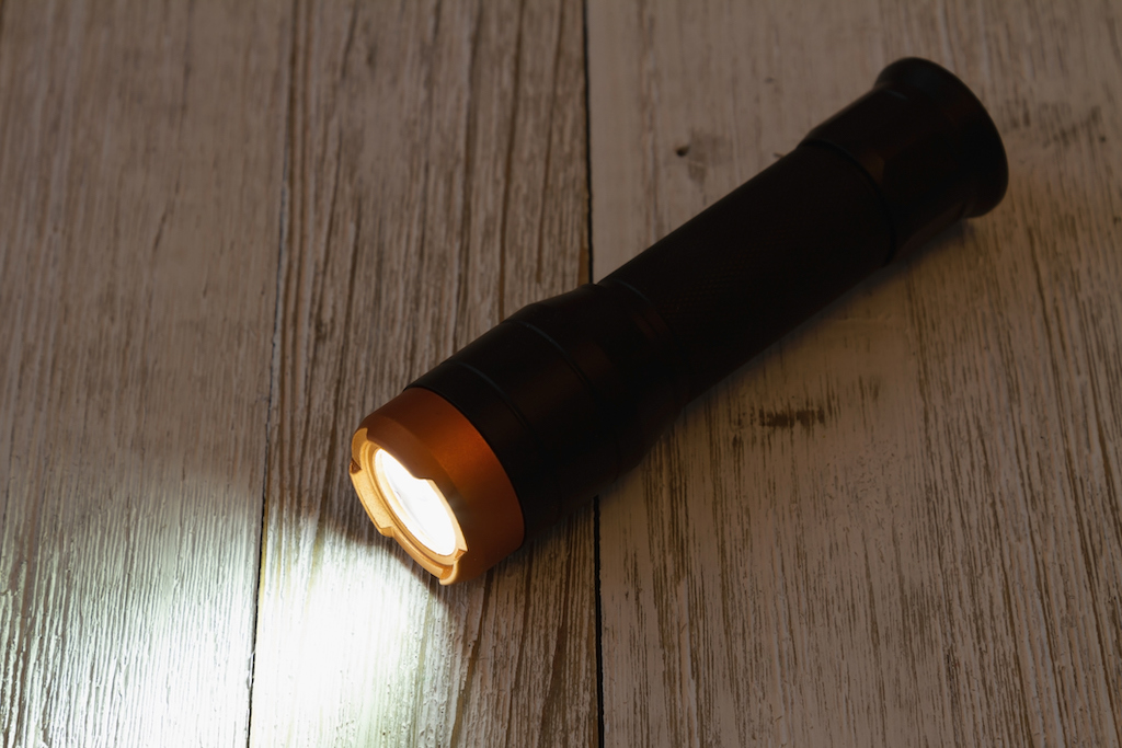 Flashlight laying on floor during power outage in a home in need of electrical repair.