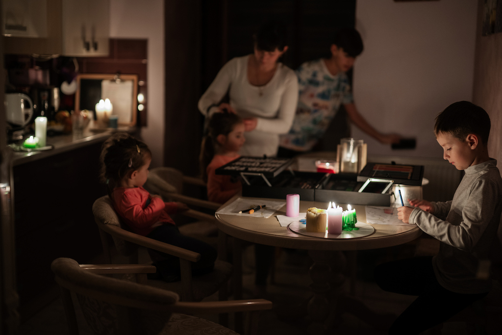Family surrounded by candles during a power outage, in need of a trusty electrical contractor.